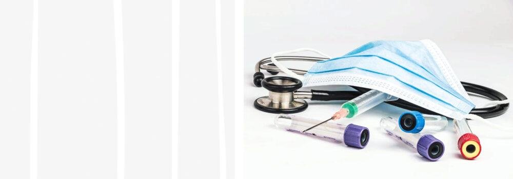 Tienda de Material Médico y de protección al mejor precio. 4 Tubos de muestras, jeringuilla con aguja y fonendoscopio con una mascarilla quirúrgica de color azul sobre una mesa