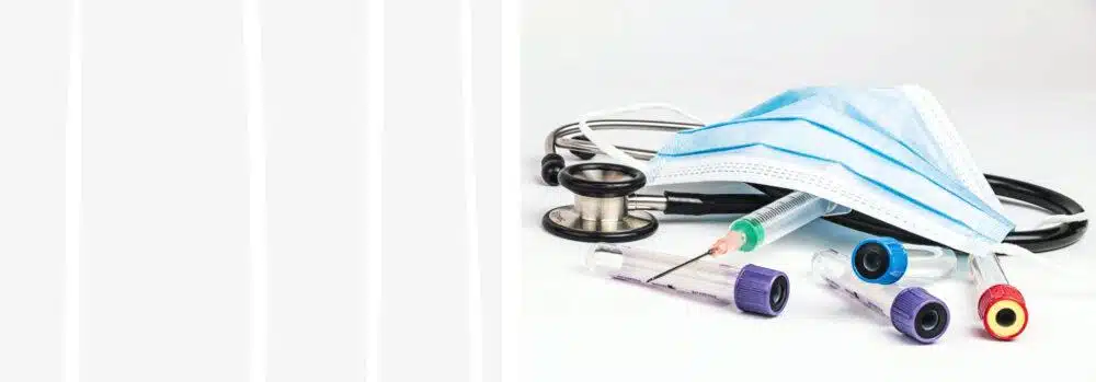 Tienda de Material Médico y de protección al mejor precio. 4 Tubos de muestras, jeringuilla con aguja y fonendoscopio con una mascarilla quirúrgica de color azul sobre una mesa