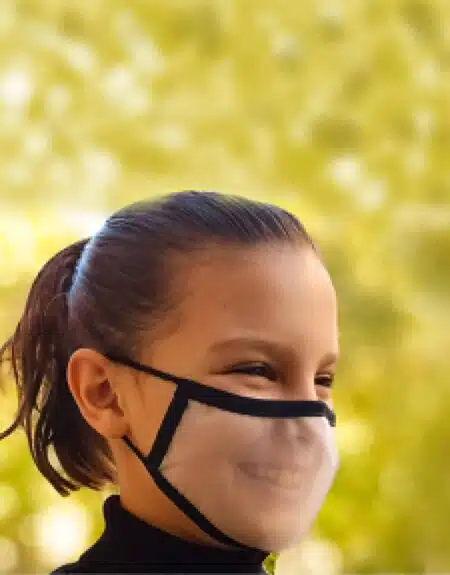 Niña llevando una mascarilla transparente reutilizable y homologada y de color negra 30 lavados